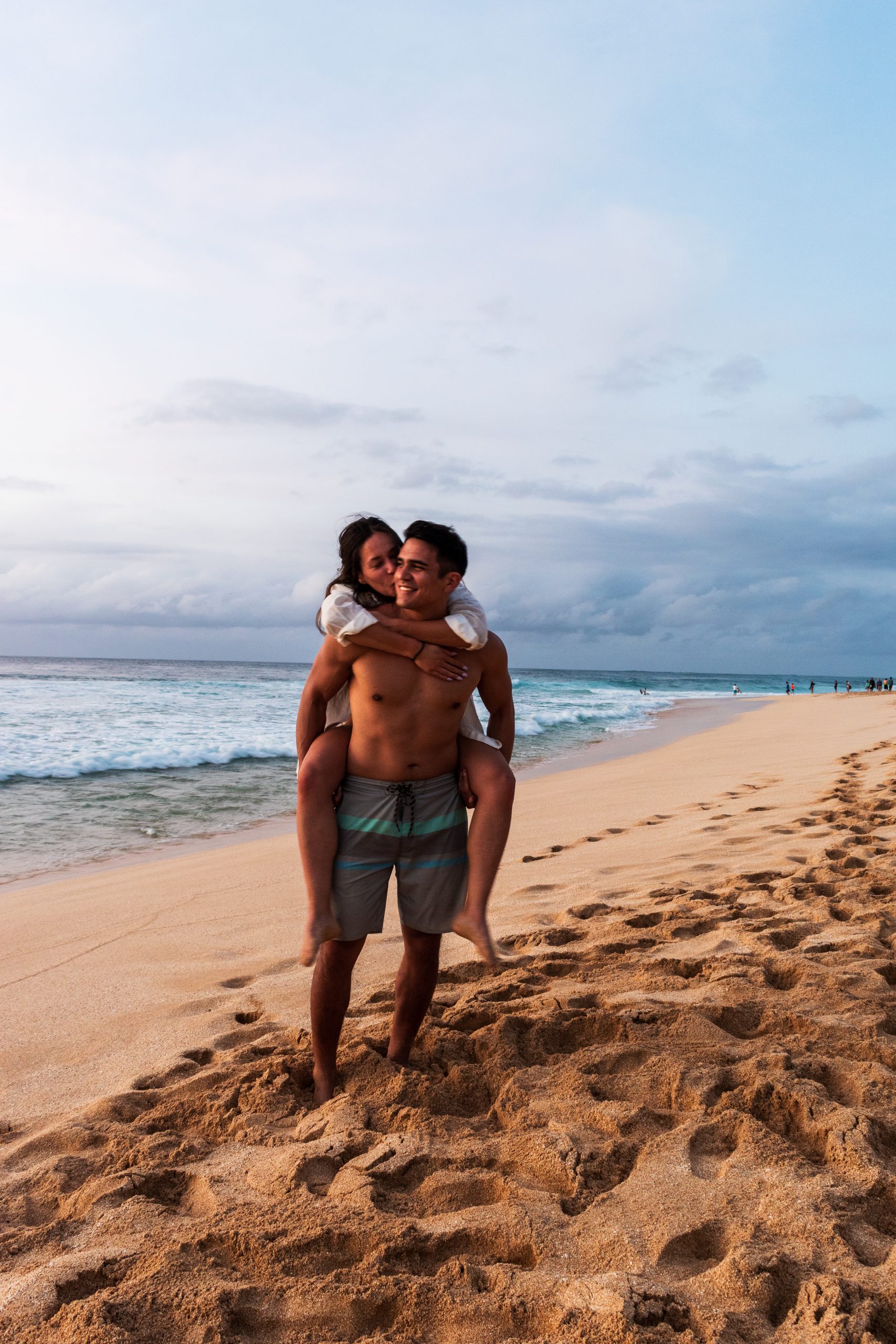 Mia and Jay on Pipeline Beach at sunset in Oahu, Hawaii