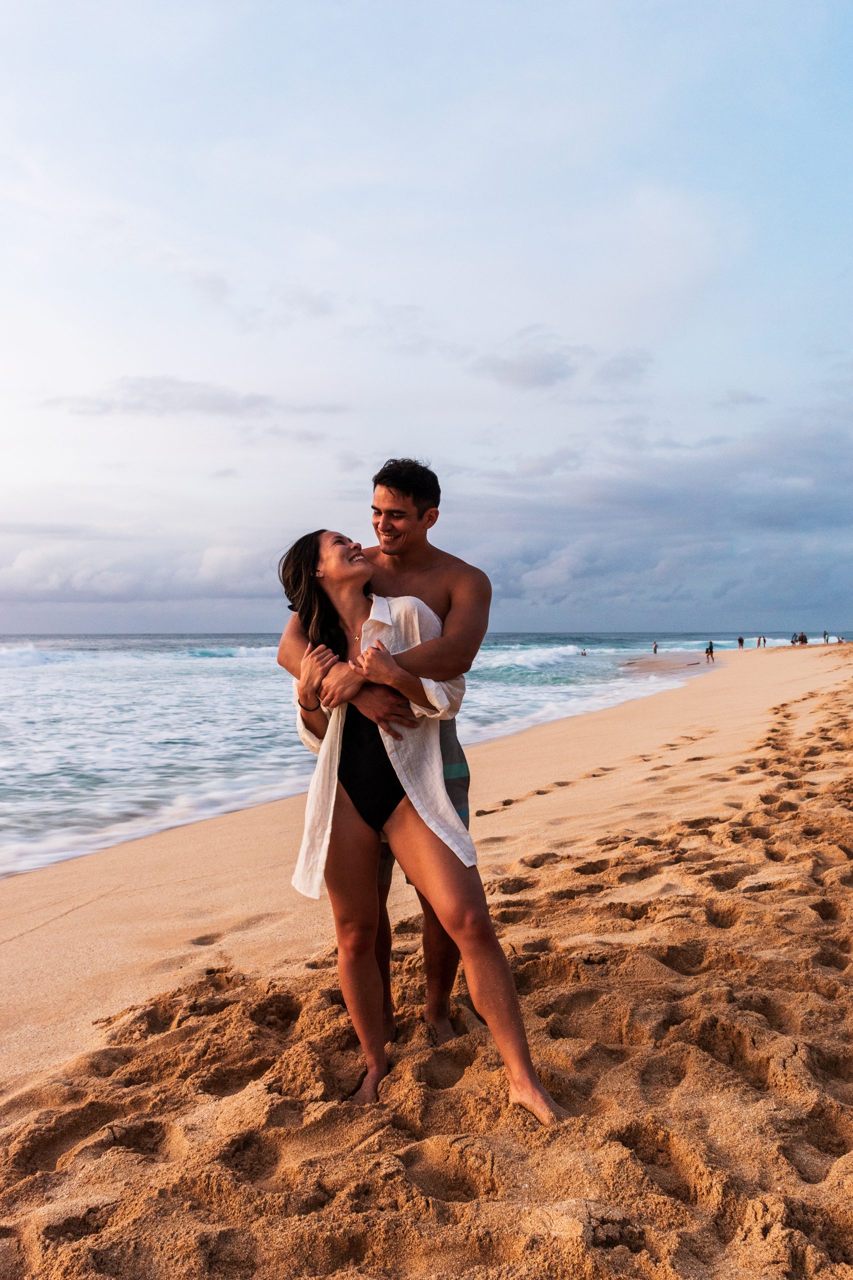 Mia and Jay embracing on the beach in Hawaii