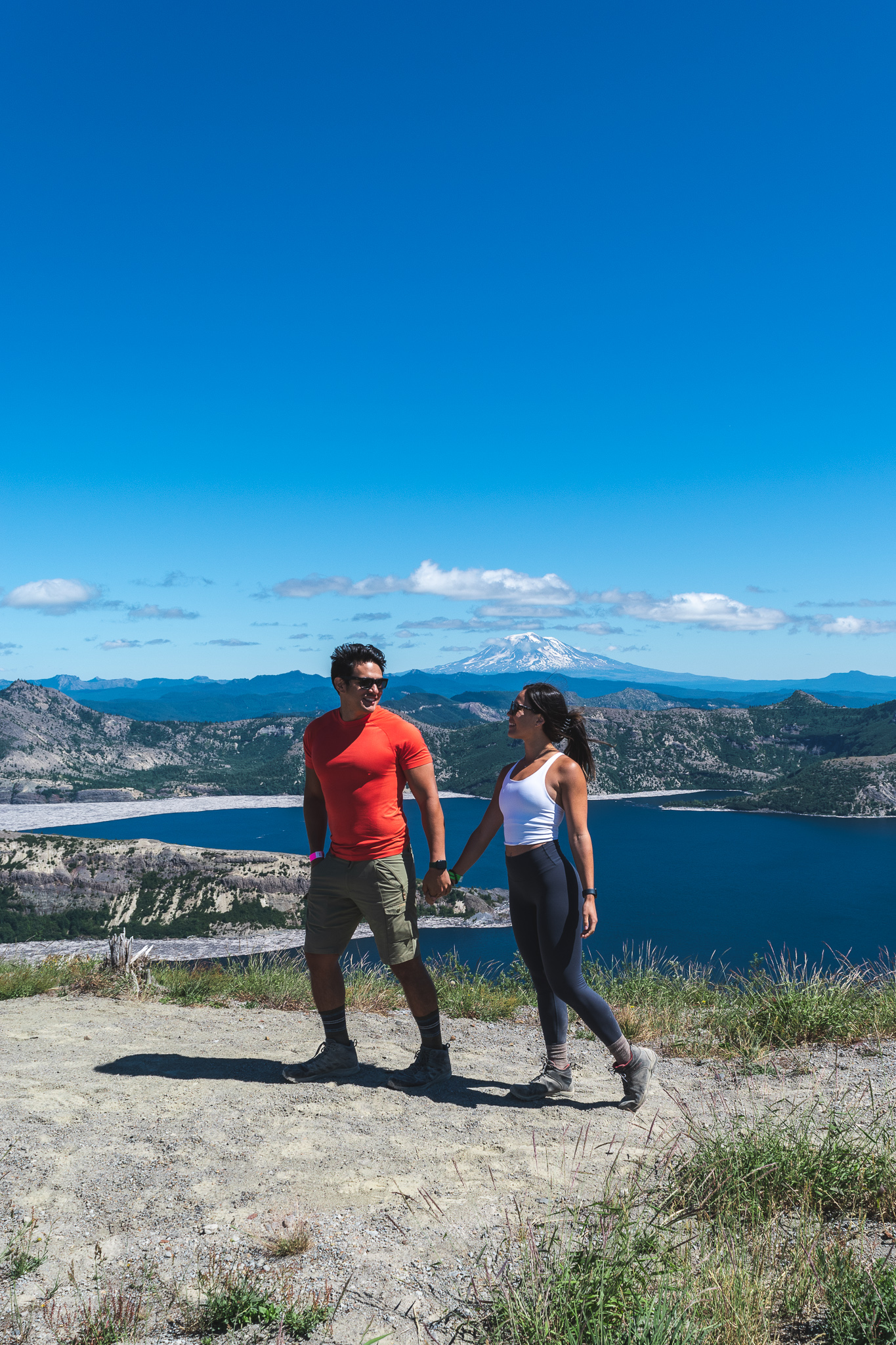 Mia and Jay holding hands in front of Spirit Lake and Mt. Adams in Washington