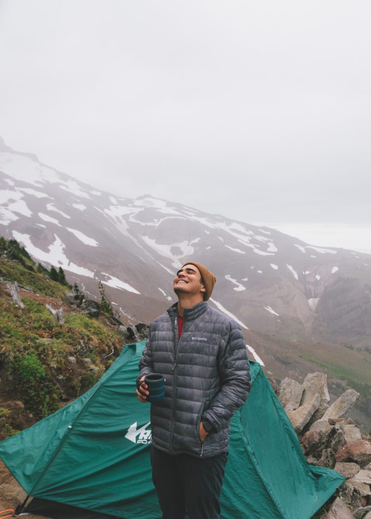 Jay smiling at the sky on Mt. Hood with our tent in the background on our backpacking trip