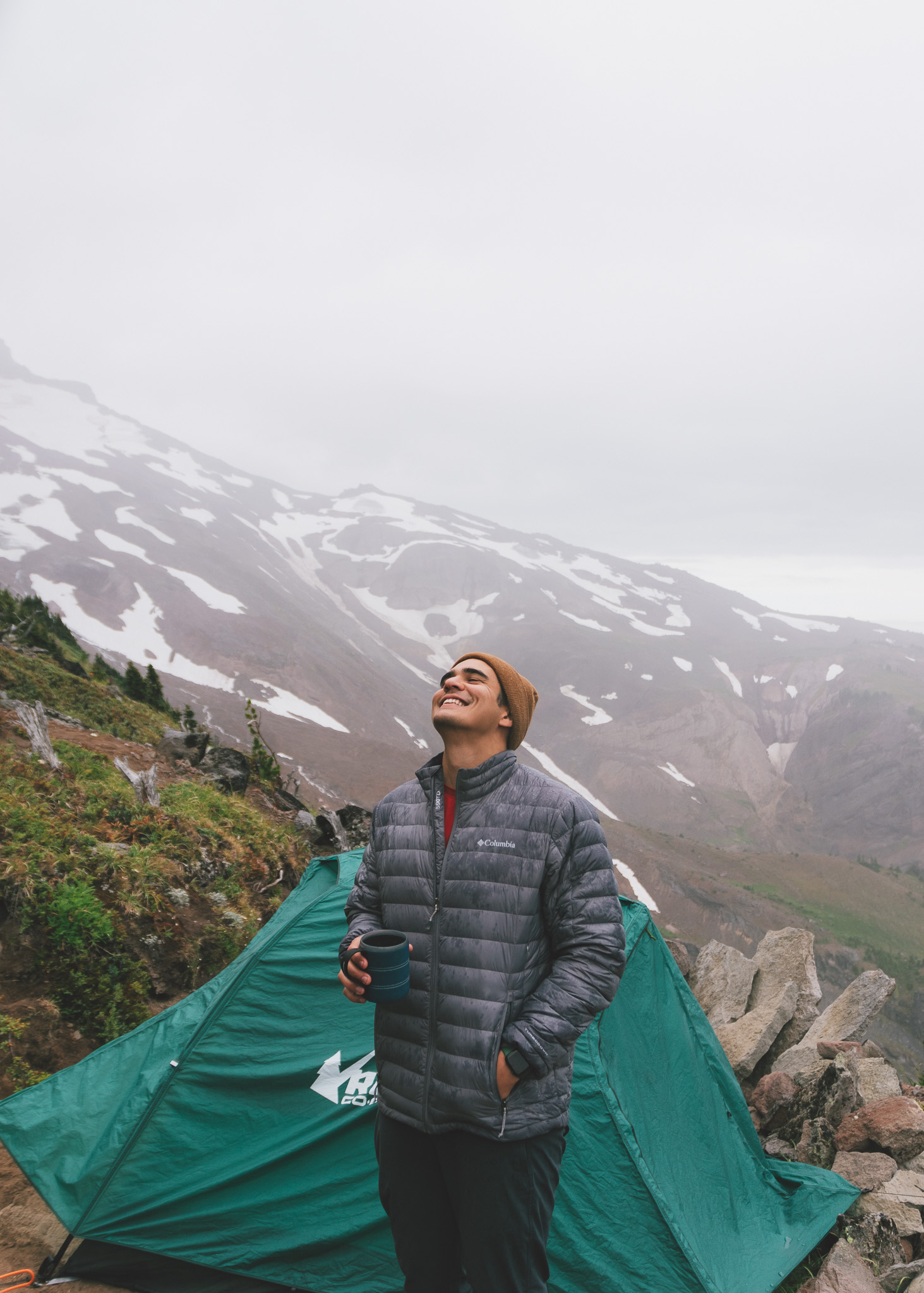 Jay smiling at the sky on Mt. Hood with our tent in the background on our backpacking trip