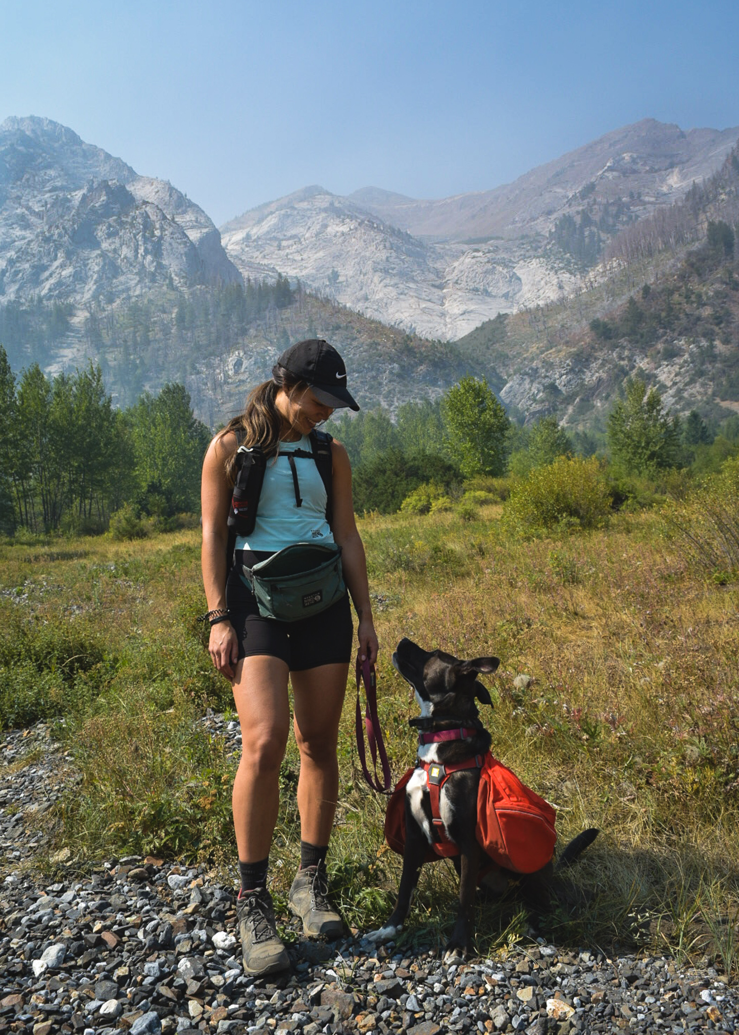 Mia and her dog Zella looking at each other with the Wallowa Mountains in the background in Eastern Oregon