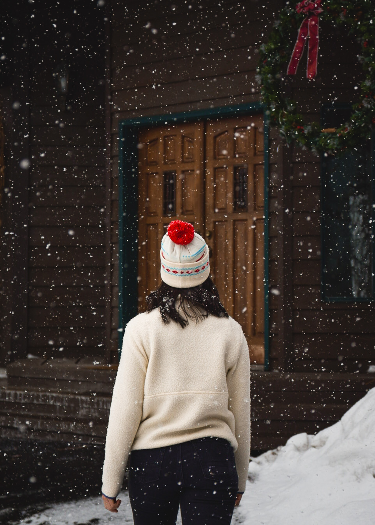 Snowy shot of Mia walking towards the front doors of Khandahar Lodge in Whitefish, Montana